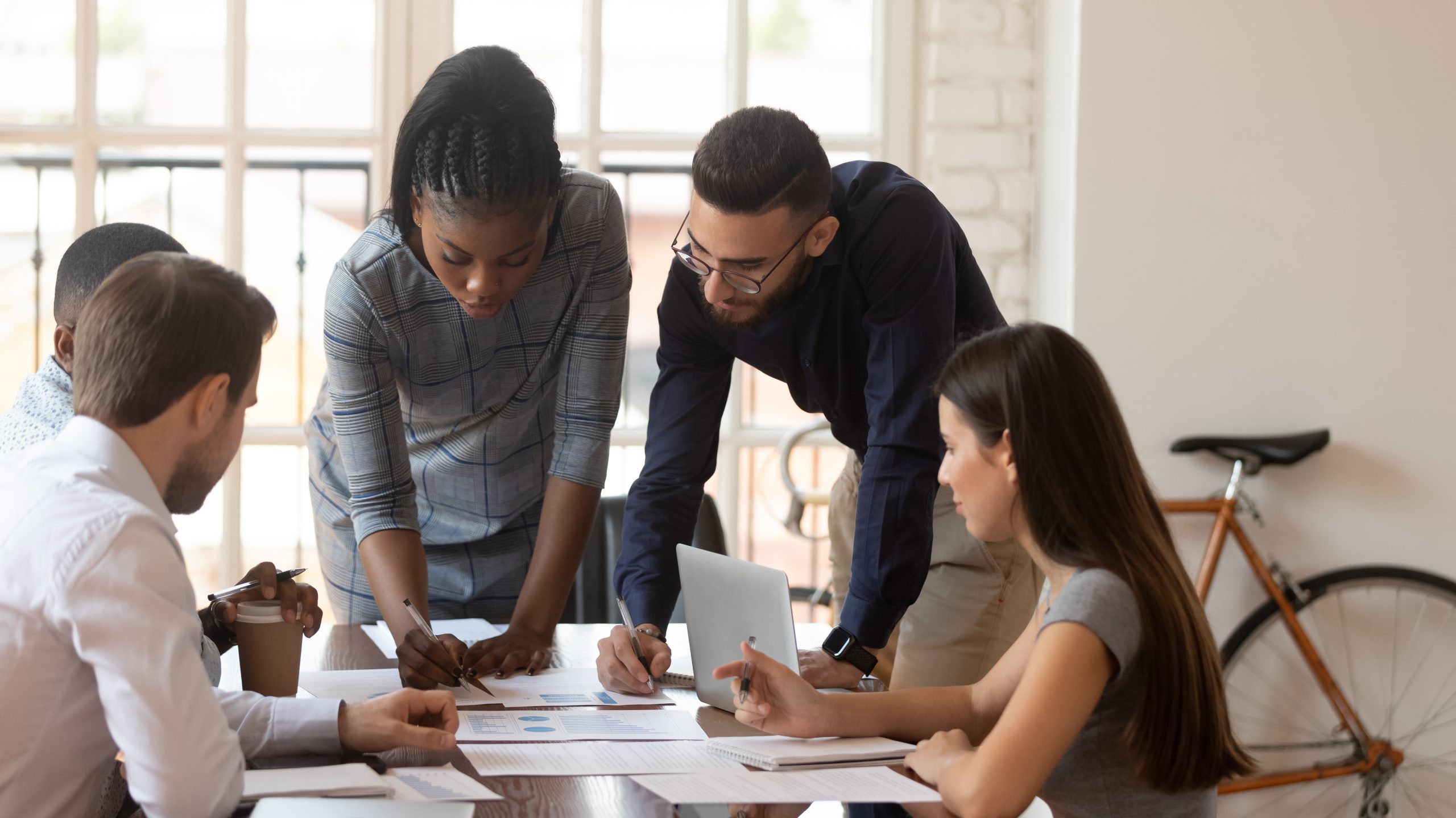 Diverse millennial colleagues brainstorm cooperating at meeting